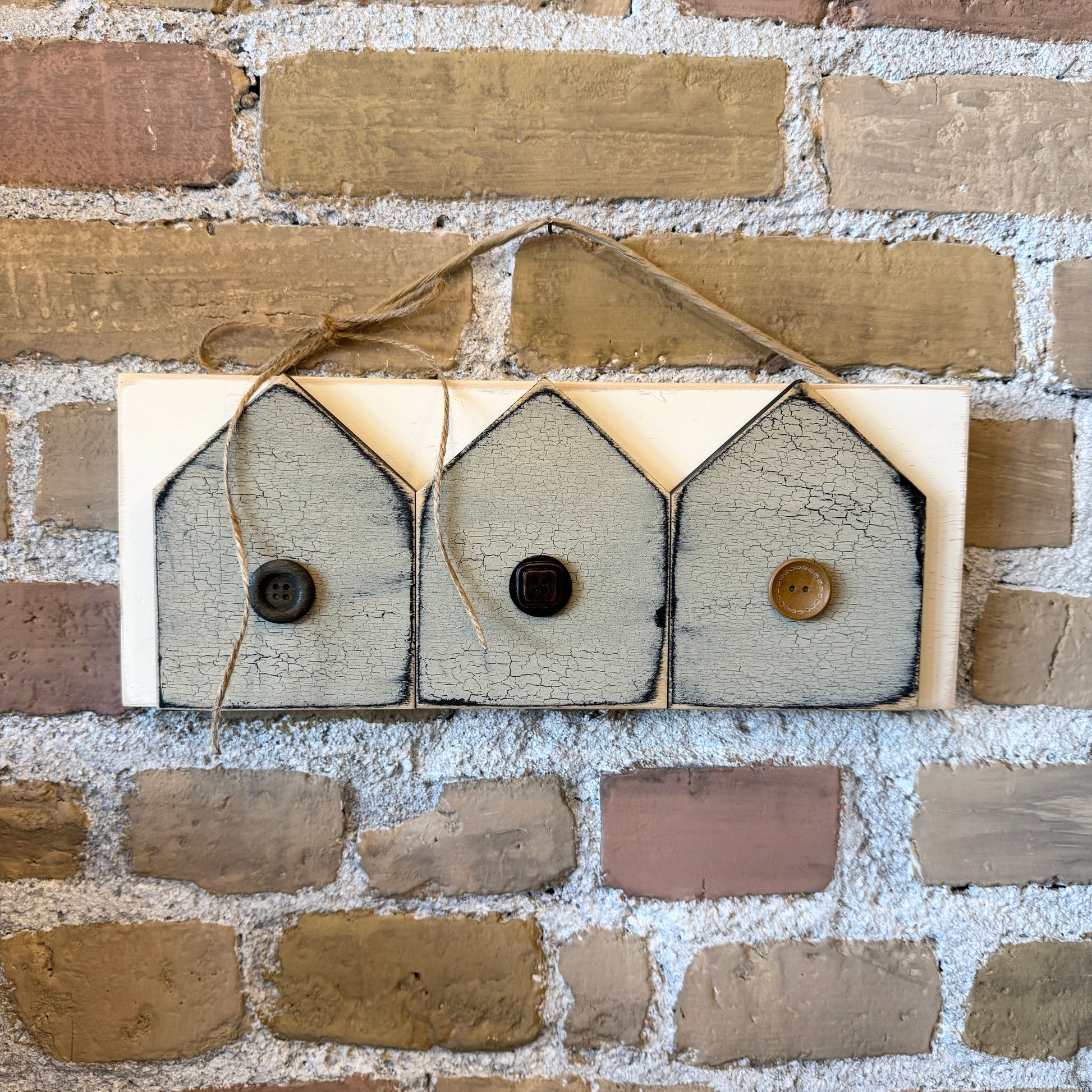 Rustic painted wood wall hanging with three houses and buttons